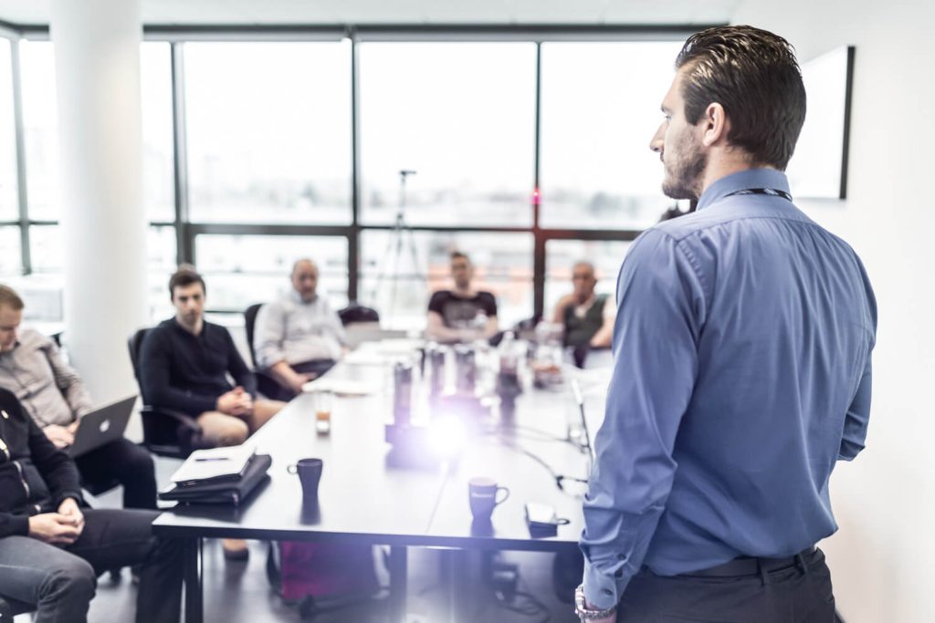 A middle-aged man providing executive presenting at a meeting - representing Nerve Strategic's executive coaching.