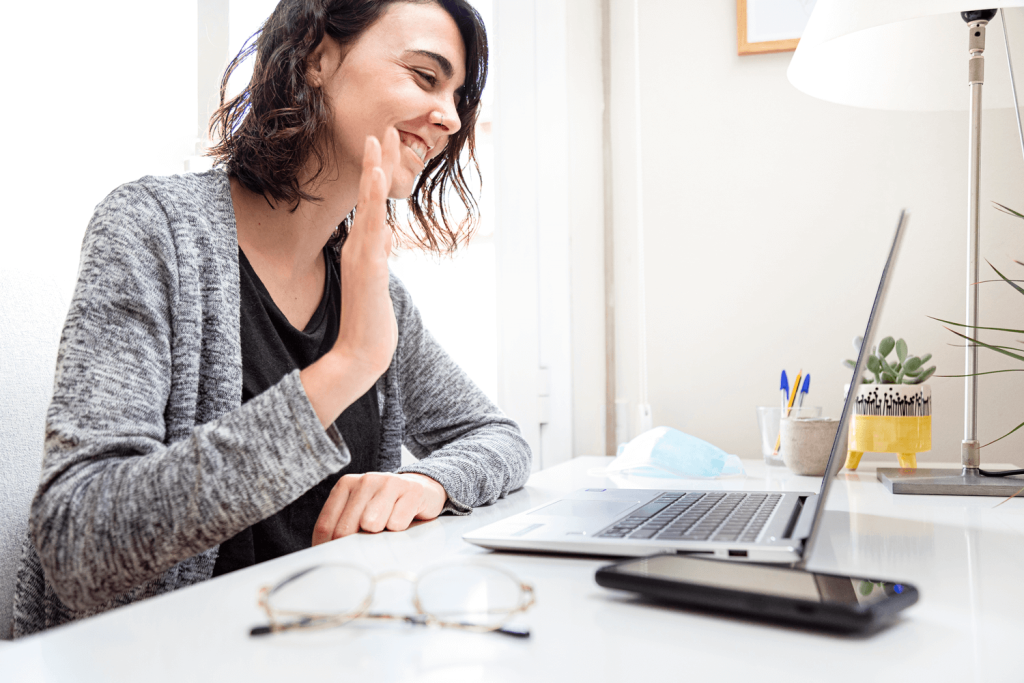 A young woman waving at the computer screen - representing Nerve Strategic's One-on-one Coaching